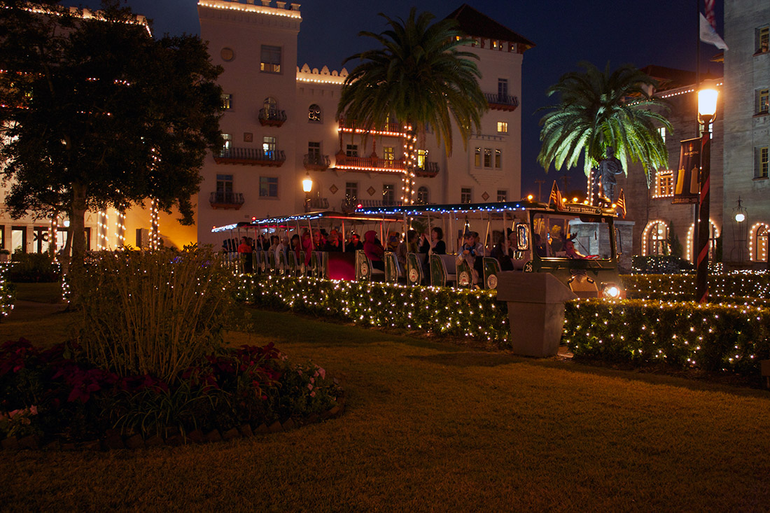 A photo of people riding the Old Town Trolley in front of the Lightner Museum during St. Augustine's Nights of Lights holiday display.