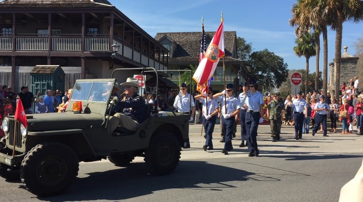 A line of veterans marching behind a drab green jeep in the veterans parade
