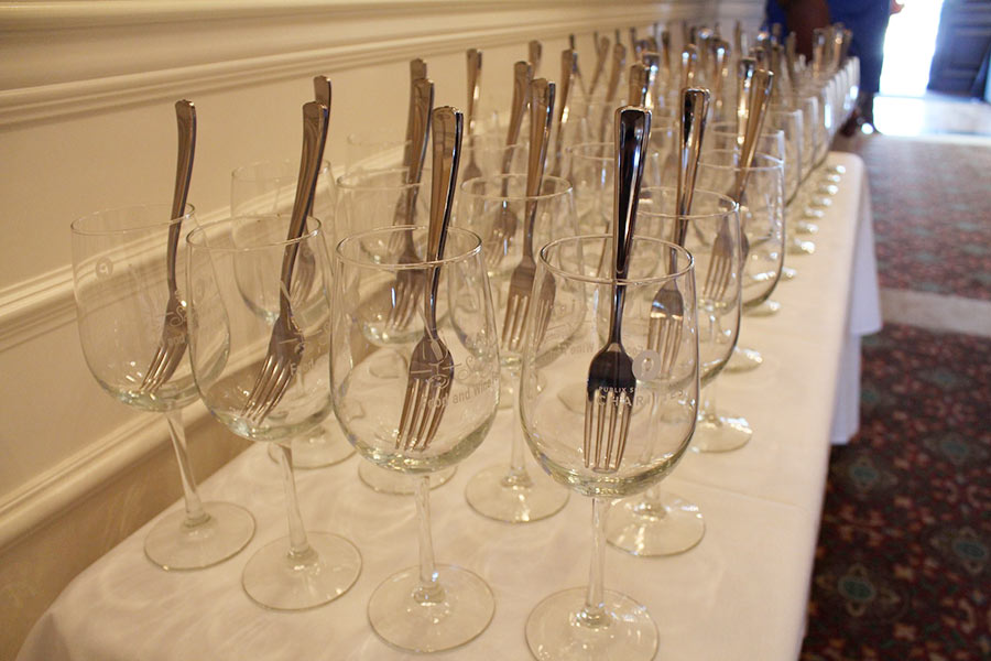 Four rows of wine glasses with a fork placed in them.