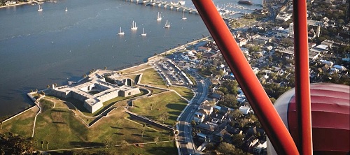 Image is an aerial view of the Castillo de San Marcos from a biplane. Image contains water, grass, and outdoors.