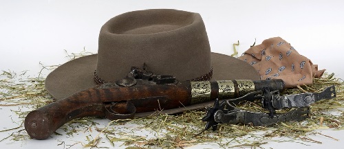 Image contains only the following props: cowboy hat, pistol, and hay.