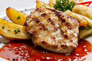 Closeup image of grilled chicken and sides.