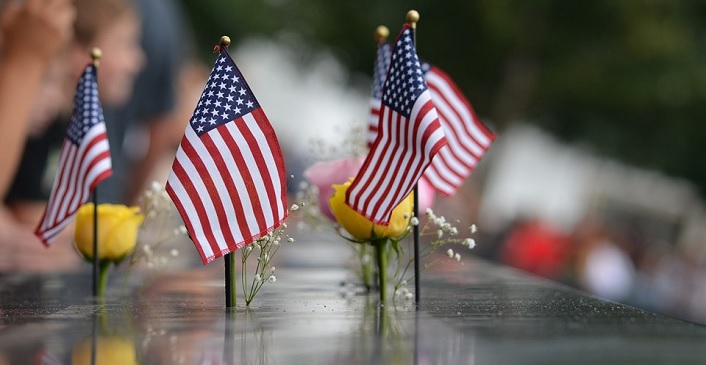 Image contains several flags and flowers on a memorial for September 11., Ceremony of Remembrance