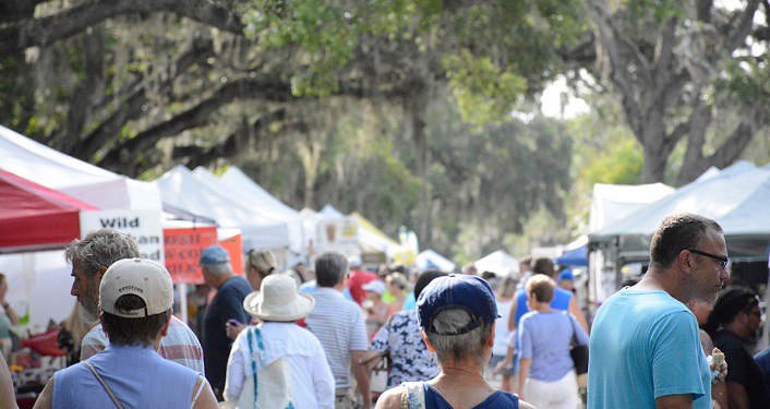 image of lots of people walking, browsing at various vendor tents set up outside at St. Augustine Amphitheatre Farmers Market