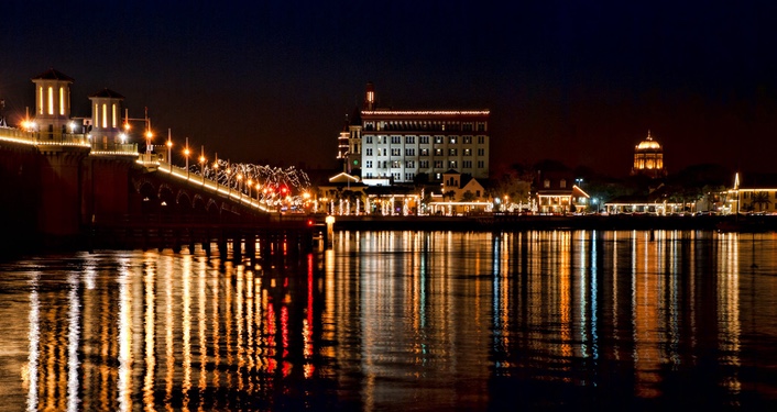 image at night from the water of Bridge of Lions and bayfront in St. Augustine lit up with millions of tiny, white lights during Nights of Lights