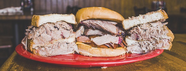 Image contains three pulled pork sandwiches on a plate.