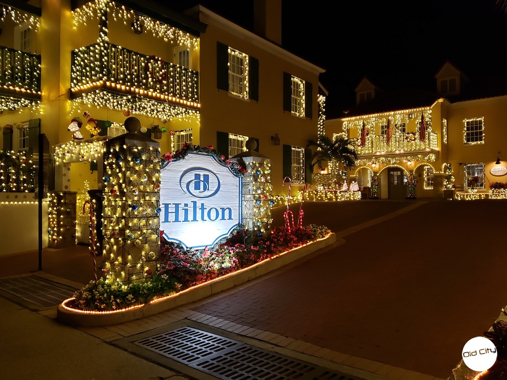 Image contains the entrance way of a hotel decorated in many holiday lights and ornaments.