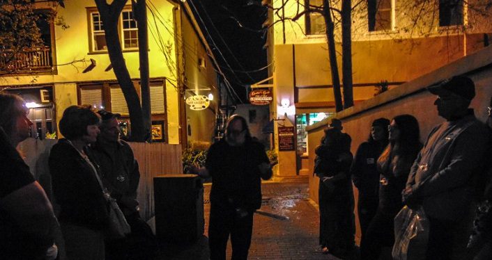 image at night with group of people gathered round tour guide on GhoSt Augustine Paranormal Tours