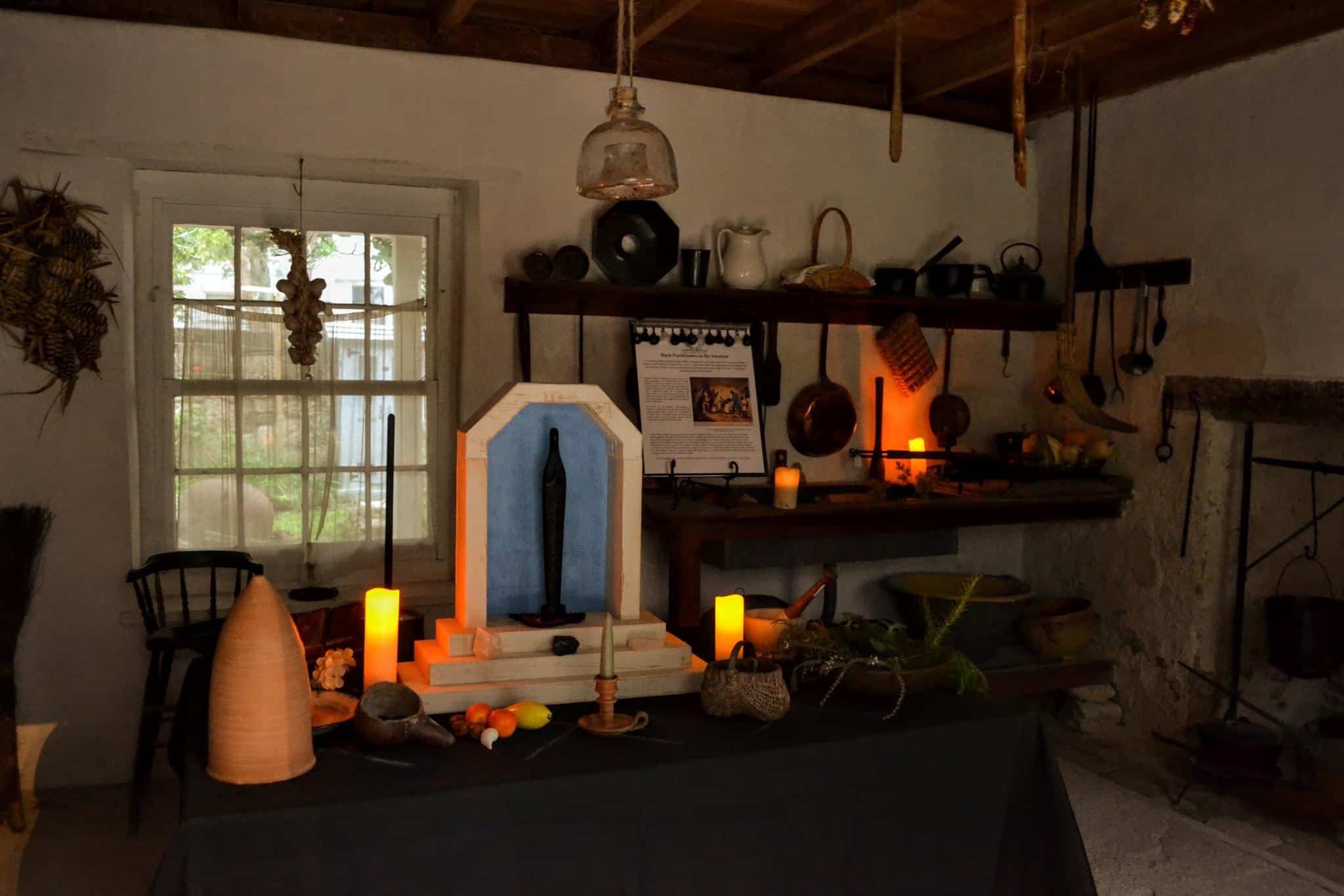 Kitchen inside the Ximenez-Fatio House Museum, set with herbs, candles, pans, and other historic artifacts and decorations.