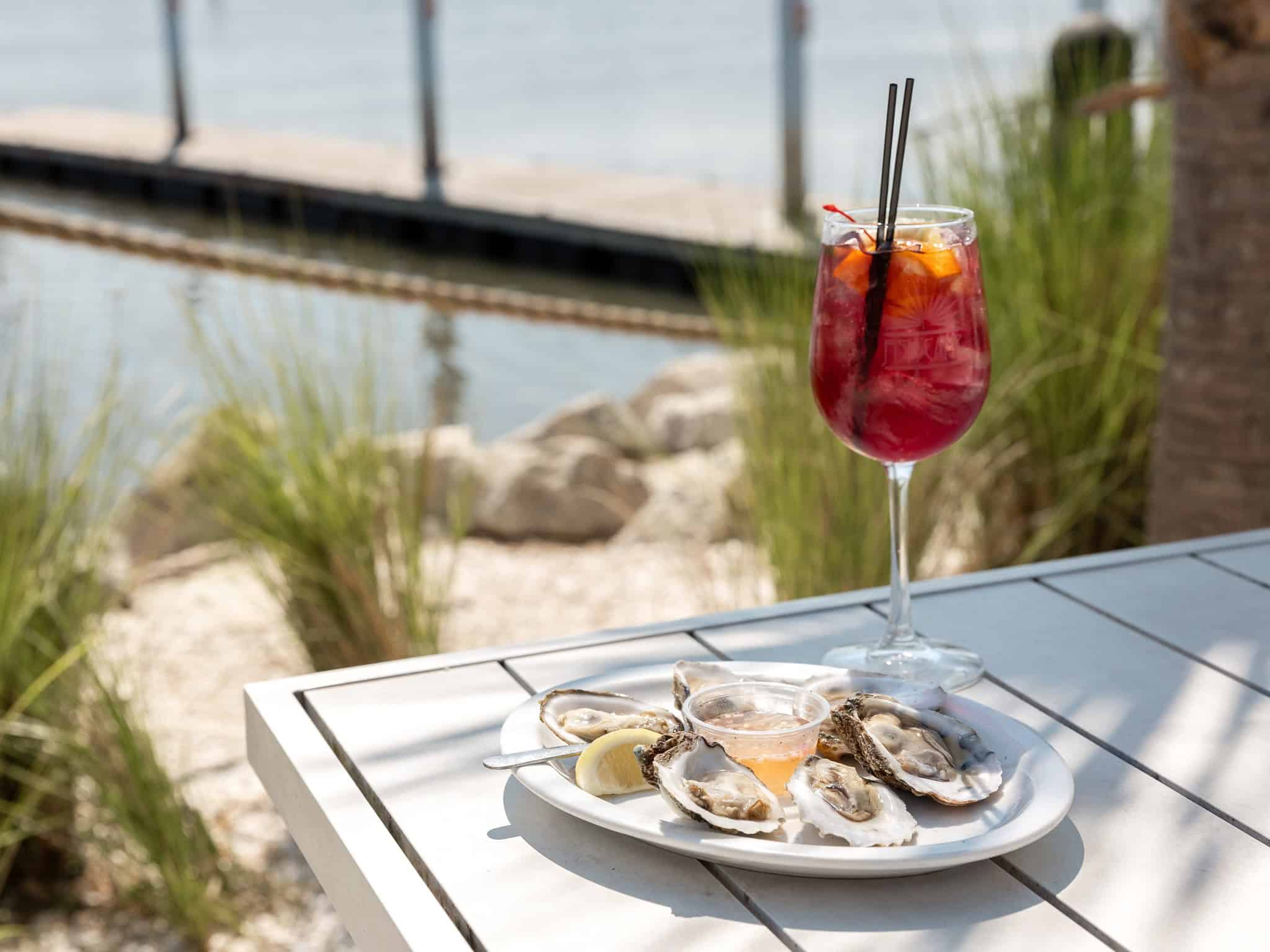 Picture of a colorful fruity drink and scallops on an outdoor patio table at the St. Augustine Fish Camp.