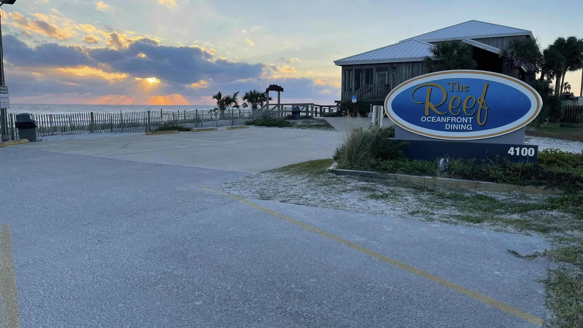 Outdoor view of The Reef Restaurant with a sunset in the background.