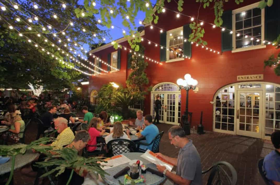 People eating outside under twinkling lights and trees at Harry's Seafood Bar and Grille in St. Augustine.