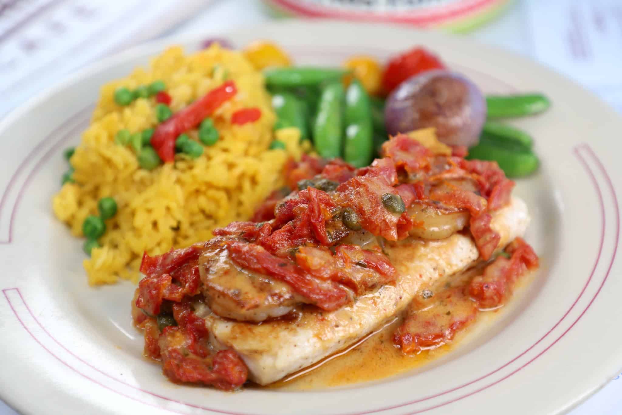 Fresh fish topped with a savory tomato, caper, and mushroom sauce, served with yellow rice and mixed vegetables at Columbia Restaurant in St. Augustine.