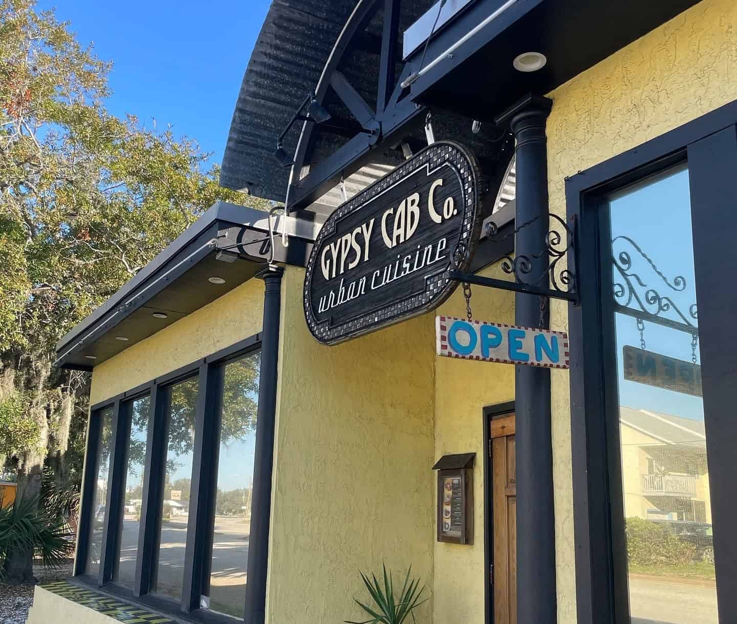 Exterior of Gypsy Cab Co. restaurant with sign reading 'urban cuisine' and a blue 'OPEN' sign, located in St. Augustine.