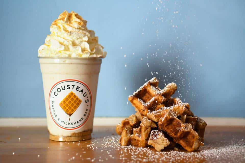 Powdered waffle and a frappe with whipped cream on a table.