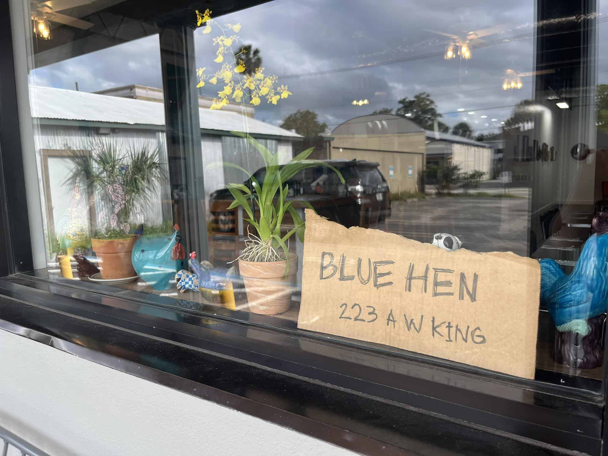 Window outside of the Blue Hen Cafe with a sign and some decorations.